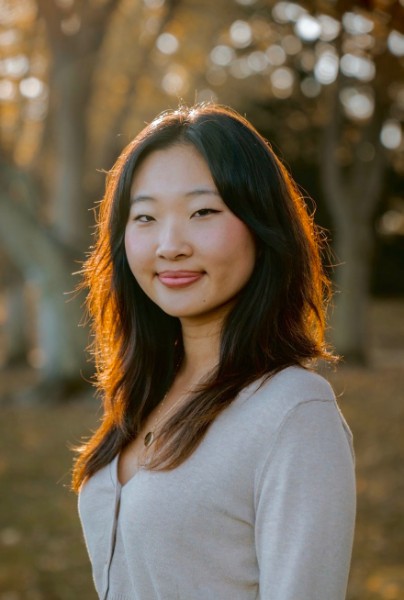Portrait of Sienna Wong, a poet, photographed outdoors in warm autumn light